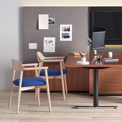 A private office featuring a peninsula desk and two Crosshatch Side Chairs with blue seat pads and wood frames.