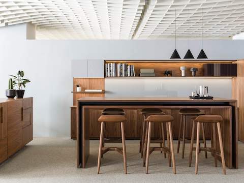 An open collaboration space featuring a rectangular Peer Table and six wood Crosshatch Stools with a medium finish.