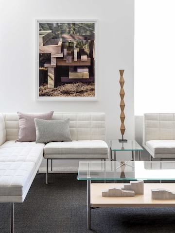 A lounge featuring a rectangular Layer coffee table with a glass top and wood shelf, complemented by off-white Tuxedo Component Lounge Seating.