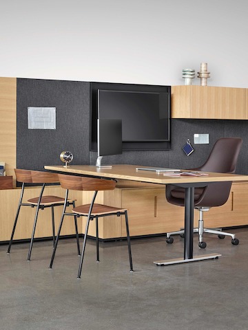 An executive office featuring Geiger Rhythm Casegoods, a peninsula desk, a brown Saiba office chair, and two Leeway side chairs.