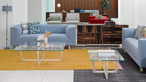 An executive lounge furnished with two glass-top Loophole occasional tables, a Domino Storage credenza, and two light blue Rolled Arm sofas.