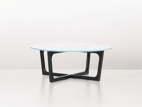 A round Loophole coffee table with a glass top and black wood base.