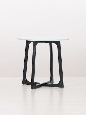 A round Loophole side table with a glass top and black wood base.