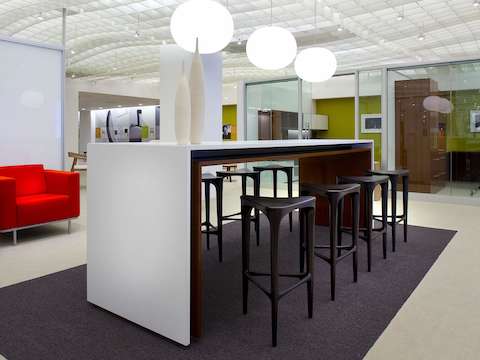 An open interaction space featuring a white Peer Table and dark brown 2 by 3 Stools to support collaboration.
