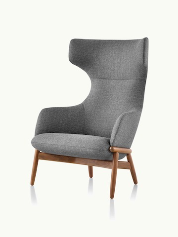Angled view of a wing-back Reframe lounge chair with dark gray upholstery and a wood frame in a medium finish.