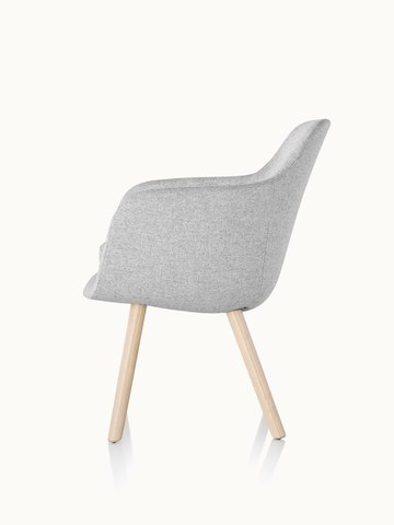 Side view of a Saiba Side Chair with light gray upholstery and wood legs in a light finish.