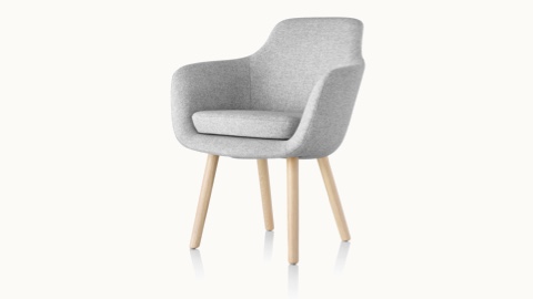 Angled view of a Saiba Side Chair with light gray upholstery and wood legs in a light finish.
