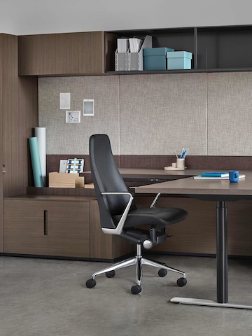 An executive office featuring a black leather Taper office chair and Geiger Rhythm Casegoods with a peninsula desk.