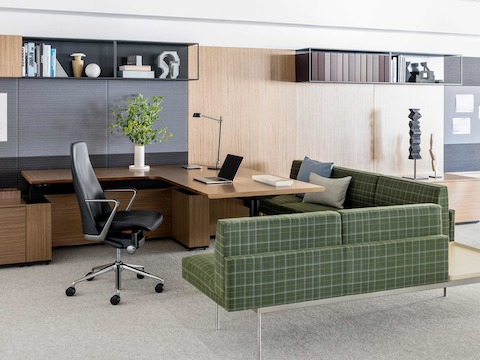 An executive office featuring a Taper office chair in black leather upholstery and Tuxedo Component Lounge Seating in green plaid fabric.