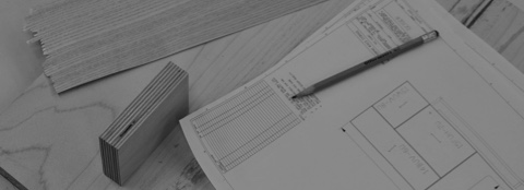 Black-and-white image of a product drawing, pencil, wood block, and shim on a wood surface. Black-and-white image of a product drawing, pencil, wood block, and shim on a wood surface.