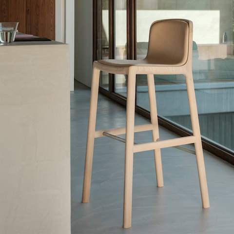 Lijn Stool designed by Carole Baijings for Geiger with leather upholstered seat and back on a matte wood frame viewed at an angle in a styled environment.