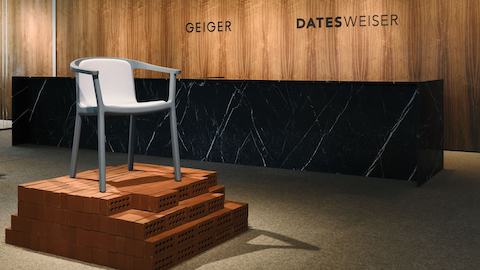 Lijn Armchair designed by Carole Baijings for Geiger in Nordic Blue wood with Maharam Luce upholstery in Brine shown at an angle on an exhibition platform in the Geiger DatesWeiser showroom.