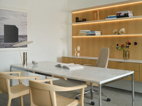 Geiger One Casegoods in Nordic Oak veneer shown at an angle with freestanding Parsons table with white marble top, Taper chair, and two Lijn Armchairs for guests in a private office setting.