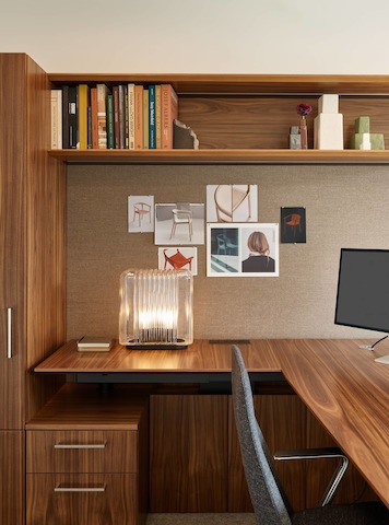 Geiger One Casegoods in Natural Flat Cut Walnut with a Geiger Taper Chair by Mark Goetz viewed from the side with office accessories including a table lamp and books in overhead storage, in a private office in the Geiger DatesWeiser Chicago Showroom.