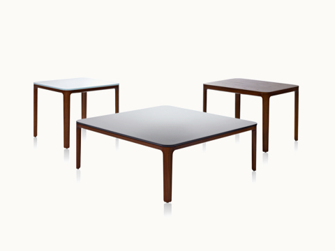 Three A Line occasional tables, including two square tables with glass tops and one rectangular table with a veneer top, all with solid wood legs. Three A Line occasional tables, including two square tables with glass tops and one rectangular table with a veneer top, all with solid wood legs.