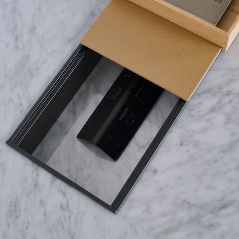 Ascent Conference Table, designed by EOOS for DatesWeiser, shown in White Carrara Marble with power troughs partially covered with Prone leather in Meander, viewed from above as a detail shot.