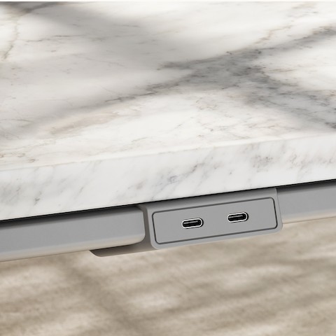 Detail of Ascent Conference Table by EOOS for DatesWeiser in White Carrara marble showing edge with power access in medium grey viewed at an angle.