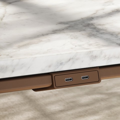 Detail of Ascent Conference Table by EOOS for DatesWeiser in White Carrara marble showing edge with power access in medium bronze viewed at an angle.