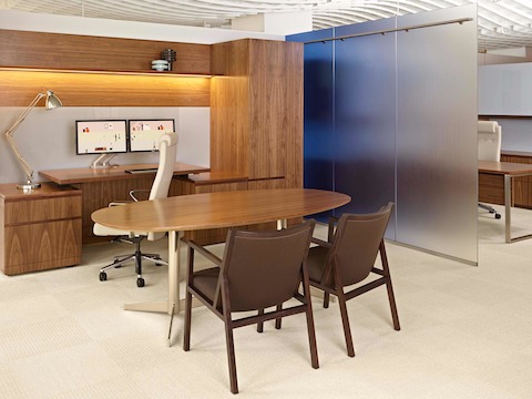 A semi-private office featuring two brown Ascribe guest chairs, an oval desk, and Tablet Casegoods.