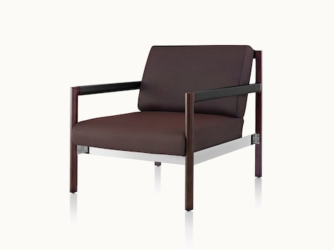 Angled view of a Brabo club chair with dark brown upholstery, leather and metal accents, and an exposed wood frame.