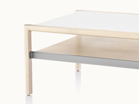 Partial view of a Brabo coffee table, showing the mix of materials, including a white leather-wrapped top, ash lower shelf, and metal frame supports.