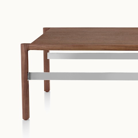 Partial front view of a rectangular Brabo coffee table with a walnut top, walnut frame, and steel-plated metal frame supports.