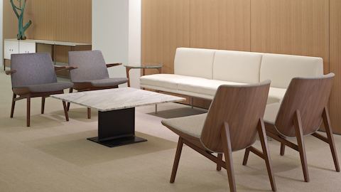 A sitting area featuring four gray Clamshell Lounge Chairs, an off-white Tuxedo Component sofa, and an I Beam occasional table.