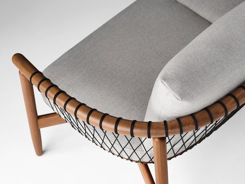 A detailed shot of a Crosshatch Settee with a walnut frame, black cords, and light neutral fabric. Viewed from the back at an angle.