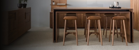 An open collaboration space featuring a rectangular Peer Table and six wood Crosshatch Stools with a medium finish.