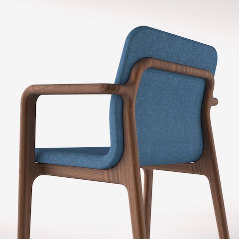 Angled view of a Deft side chair with blue fabric and a wood frame in a medium finish.