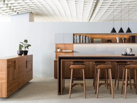 A Domino Storage sideboard forms a boundary in an interaction space that includes a standing-height Peer Table with six Crosshatch Stools.