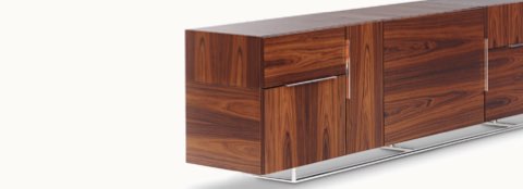 Partial angled view of a Domino Storage credenza with a dark wood finish and various modules featuring a mix of grain direction.