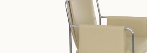 Partial side view of an Envelope side chair with beige leather upholstery, showing the seat, back, and arms.