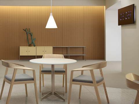 An interaction space with three Full Twist Guest Chairs around a table in the foreground and an H Frame Storage credenza against the back wall.