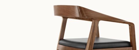 Close-up of the sculpted arms and back on a Full Twist Guest Chair with a medium wood finish, viewed from the side.