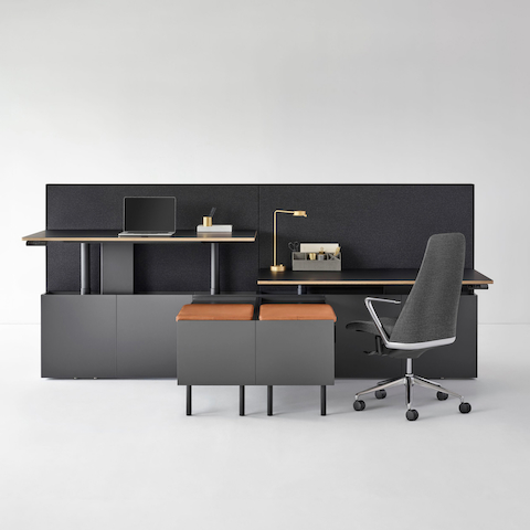 A two-pack Geiger One Casegoods bench system with accessorized workstations, one at standing height and the other at sitting height with a Taper Chair.