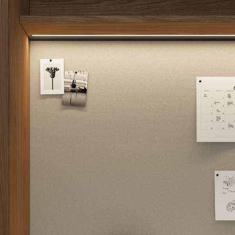 Detail shot of a Geiger One Private Office in Natural Flat Cut Oak with an overhead LED light and tack-board with a calendar and pictures pinned to it.