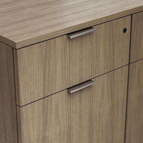 Detail shot of the Geiger One Casegoods modern tab pull option in Chrome on a Natural Flat Cut Walnut drawer front viewed from an angle.