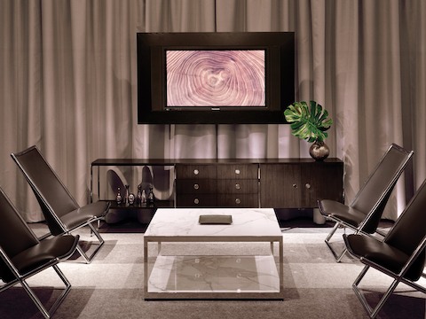 An interaction space furnished with a three-unit H Frame Storage credenza, a square H Frame Table, and four black leather Scissor Chairs.