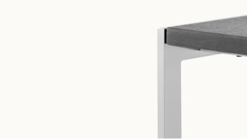 The upper portion of an H Frame side table with a metal frame and black wood top, viewed at an angle.