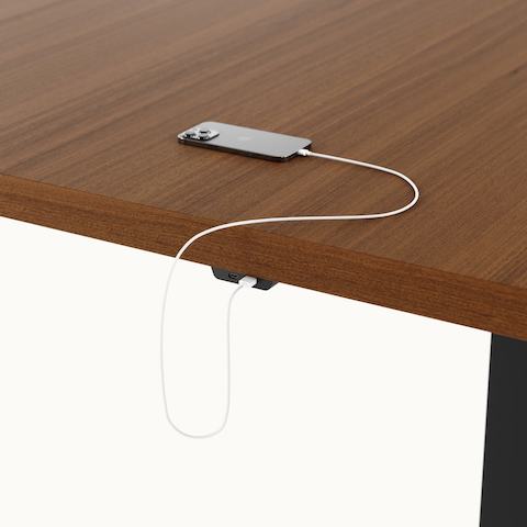 Detail shot of undermount power access on a rectangular JD Conference Table by DatesWeiser with a Natural Quarter Cut Walnut tabletop and Black base.