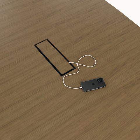 Detail shot of tabletop power access on a boat-shaped JD Conference Table by DatesWeiser in Natural Flat Cut Walnut.