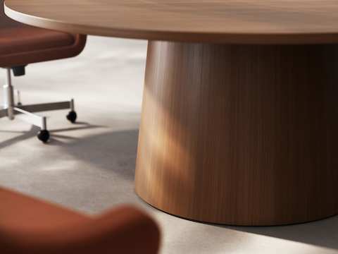 Detail of JD Meeting Table by DatesWeiser showing tapered round base in natural quarter cut walnut with two bumper chairs on a concrete floor.
