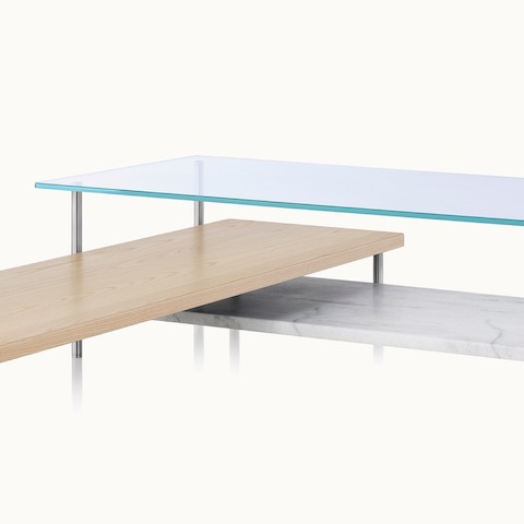 Angled view of an L-shaped Layer coffee table with a glass top, white marble lower shelf, and intersecting wood shelf with a light finish.