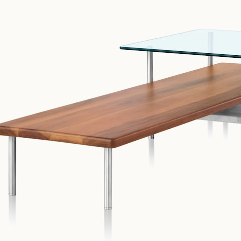 Partial view of an L-shaped Layer coffee table, focusing on the soft corners and cylindrical metal legs.