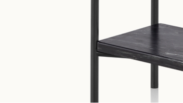 Partial view of a Layer side table, focusing on the black marble lower shelf and black cylindrical legs.