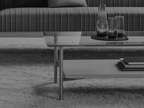 Black-and-white image showing a partial view of a rectangular Layer coffee table in front of a plaid sofa. Black-and-white image showing a partial view of a rectangular Layer coffee table in front of a plaid sofa.