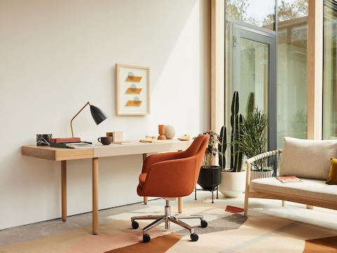 A home office setting with the Leatherwrap Sit-to-Stand Desk, Saiba office chair and Crosshatch Settee.