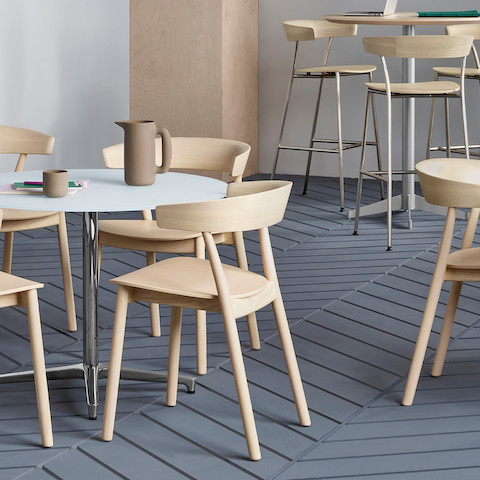 A break area featuring round tables surrounded by all-wood Leeway side chairs or Leeway Stools made of metal and wood.