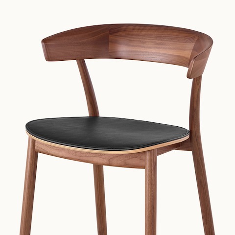 Partial angled view of a Leeway side chair, showing a solid wood frame with a medium finish.